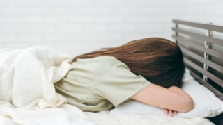 ベッドで横向きに寝ている女性