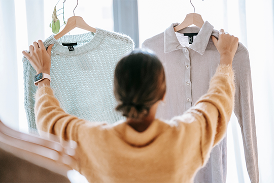 面接のために服を選ぶ女性の後ろ姿。ASD特性を持つ人が面接時の服装について悩む様子を象徴するイメージ。