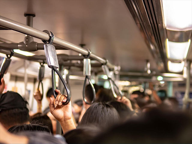 通勤時間帯の混雑した電車内の様子、手すりを持つ乗客たち