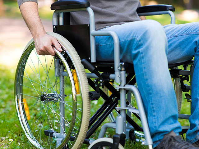 屋外で車椅子を操作している男性の写真、草の上で移動している様子