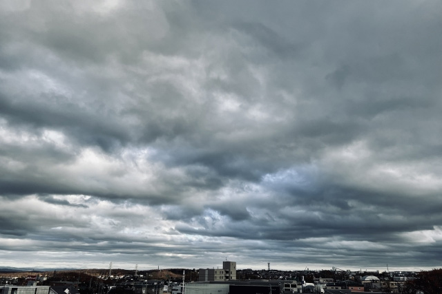 分厚い雲に覆われた空と街の風景の写真