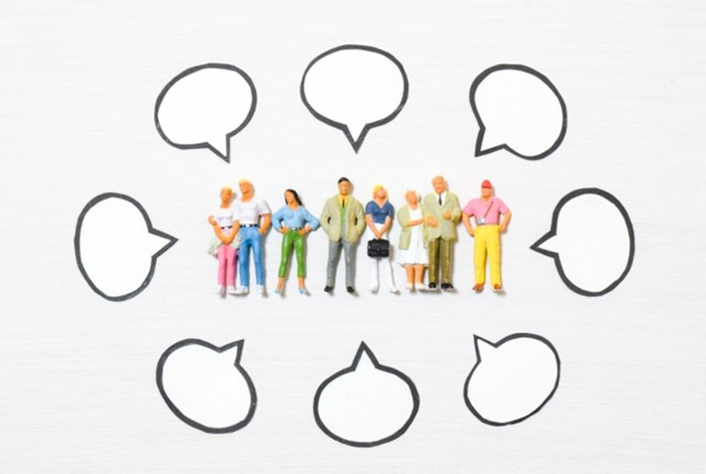 コミュニケーションを象徴する吹き出しと、人々のフィギュアのイメージ。会話や交流をテーマにした写真。