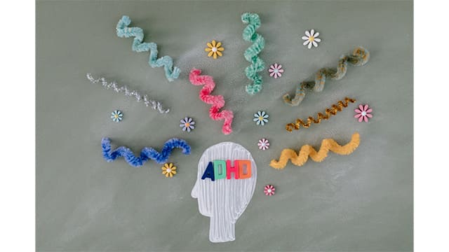 「ADHD」と書かれた頭部シルエットの周りにカラフルな装飾や波状のモチーフが広がる、発達障がい・神経多様性をイメージしたコンセプトビジュアル】