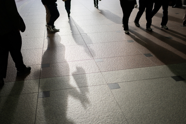 夕方の光に照らされながら街中を歩く人々の影。障害者として生きる覚悟と前を向く決意を象徴するイメージ。