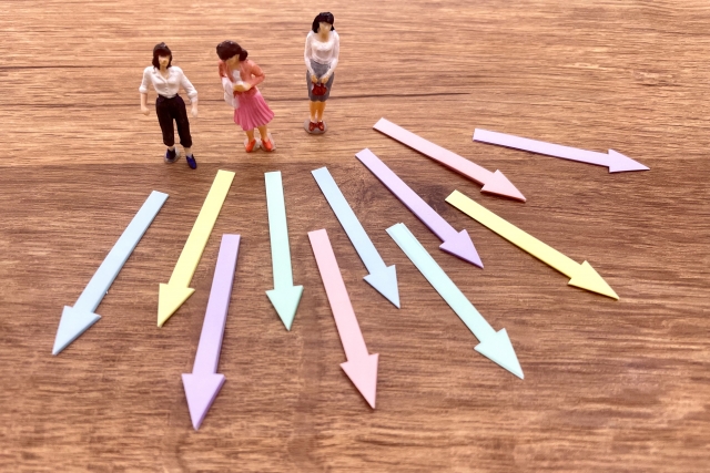 複数の進路を示す矢印の前に立つ人形。視覚障害者の職業選択やキャリアの選択肢の多様さと悩みを表現している