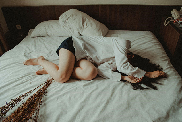 SLE（全身性エリテマトーデス）の症状による強い倦怠感でベッドに横たわる女子高校生の姿。慢性疾患と闘いながら日常生活が制限される苦しみを表現している。