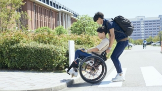 合理的配慮の実現に向けて、キャンパス内で車椅子利用者をサポートする学生の様子。障害当事者と周囲の協力によるバリアフリー推進のイメージ。